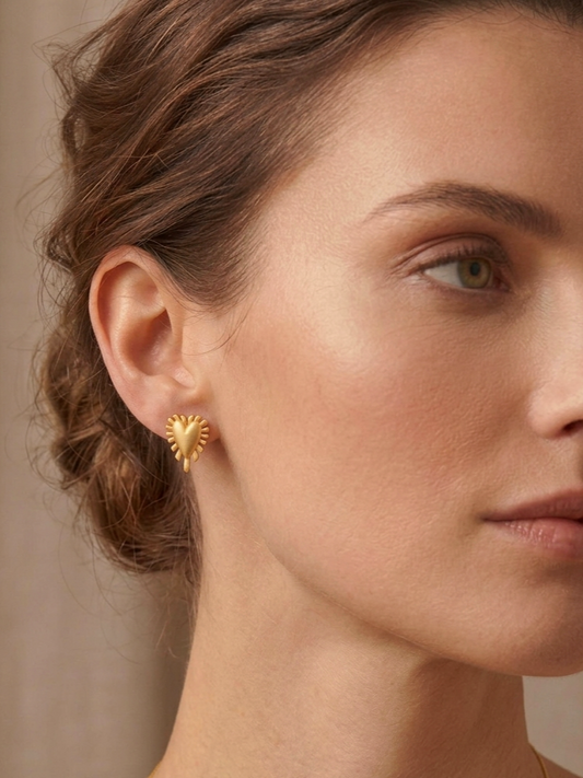Επίχρυσα ασημένια σκουλαρίκια Radial Heart της ANV Jewelry, σε σχήμα τρισδιάστατης καρδιάς με ανάγλυφες ακτίνες περιμετρικά. Ένα διακριτικό και κομψό κόσμημα που προσθέτει μια ρομαντική πινελιά σε κάθε εμφάνιση.