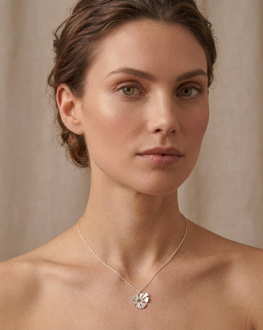 Γυναίκα που φοράει το ασημένιο κολιέ Curved Heart της ANV Jewelry από ανακυκλωμένο ασήμι 925, με το σχέδιο της καρδιάς να συμβολίζει την αγάπη και τον συναισθηματικό δεσμό.