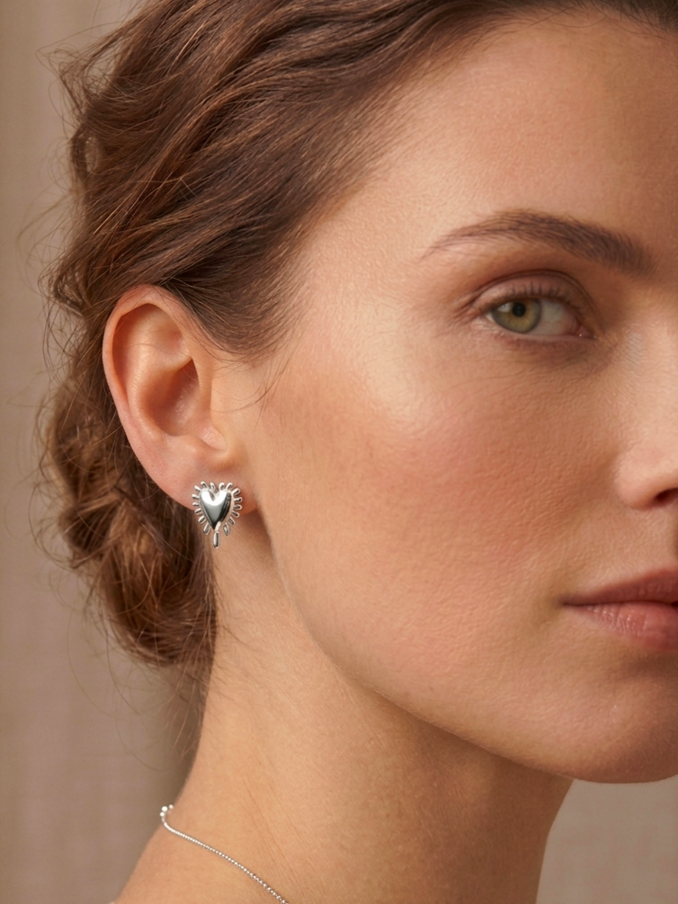 Ασημένια σκουλαρίκια Radial Heart της ANV Jewelry, σε σχήμα τρισδιάστατης καρδιάς με ανάγλυφες ακτίνες περιμετρικά. Η καρδιά συμβολίζει την αγάπη και την καλοσύνη, ενώ οι ακτίνες αντιπροσωπεύουν τη θετική ενέργεια και τη λάμψη.