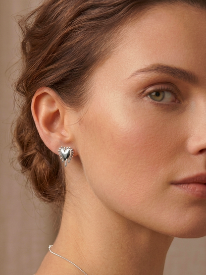 Ασημένια σκουλαρίκια Radial Heart της ANV Jewelry, σε σχήμα τρισδιάστατης καρδιάς με ανάγλυφες ακτίνες περιμετρικά. Η καρδιά συμβολίζει την αγάπη και την καλοσύνη, ενώ οι ακτίνες αντιπροσωπεύουν τη θετική ενέργεια και τη λάμψη.