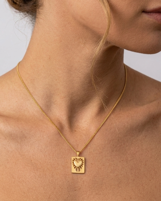 Γυναίκα που φοράει το επιχρυσωμένο κολιέ Radial Heart Talisman της ANV Jewelry από ανακυκλωμένο ασήμι 925 με επιμετάλλωση χρυσού 24Κ, με το σχέδιο της καρδιάς-φυλαχτού να συμβολίζει την προστασία και τη συναισθηματική δύναμη.